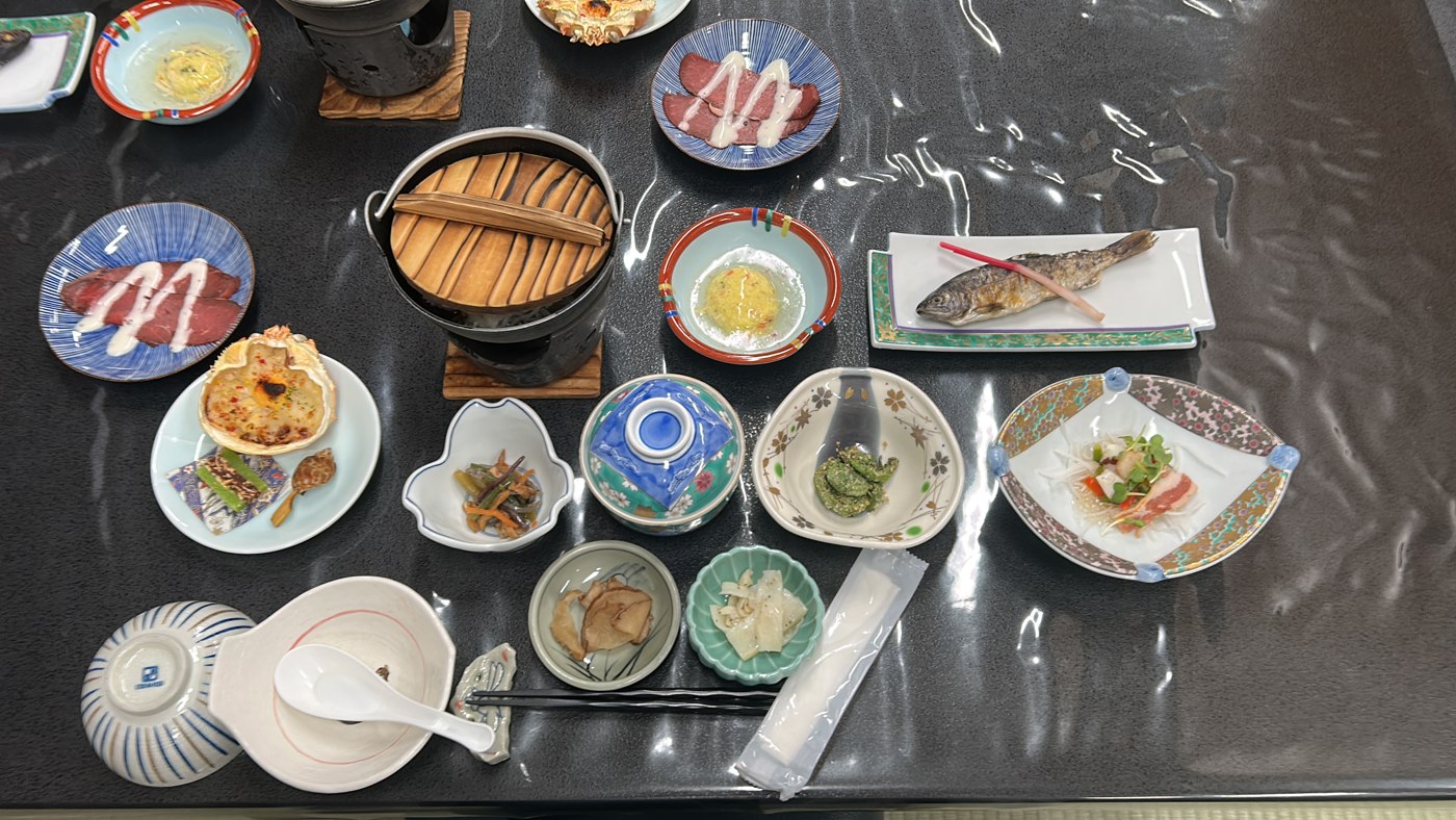 Dîner kaiseki en ryokan vu de dessus : une douzaine de petits plats, marmite individuelle et poisson grillé entier