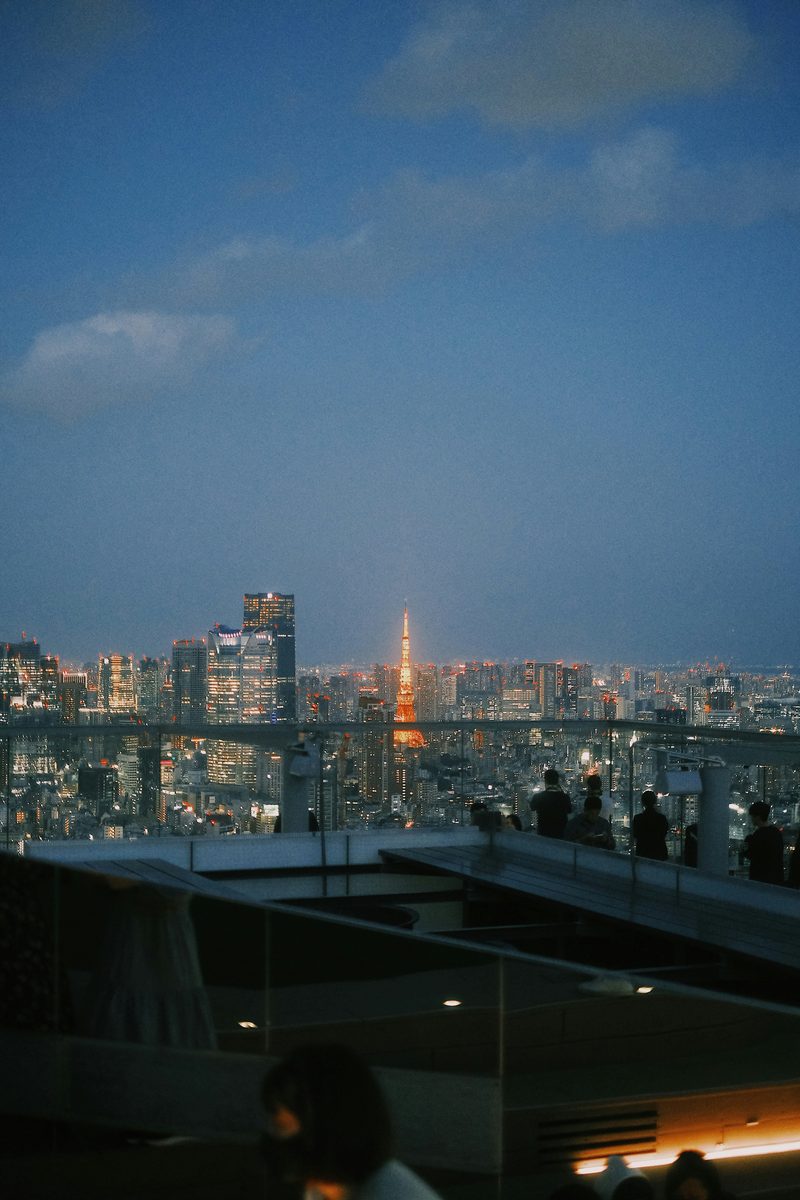 Vue de nuit depuis le toit de Shibuya Sky, la tour de Tokyo éclairée en orange au loin