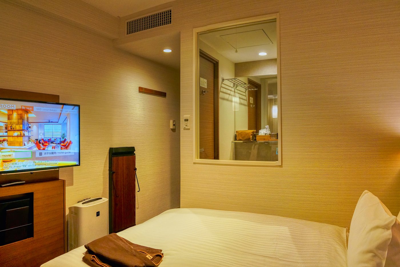 A business hotel room in Hakata: bed, wall-mounted television and a mirror by the door.