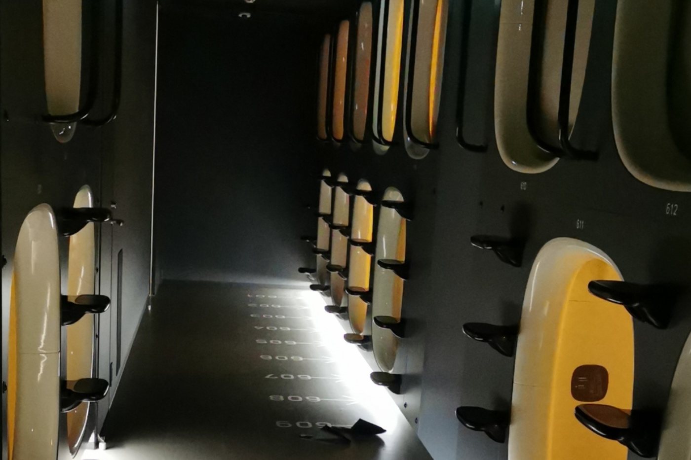 A capsule hotel corridor in Tokyo, numbered capsules stacked two levels high.