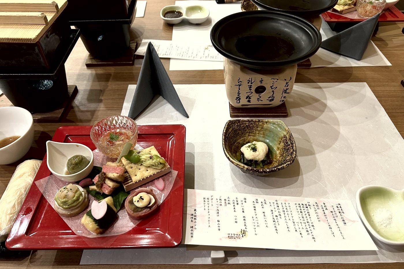 A kaiseki dinner laid out on a table: lacquer tray, small dishes and an individual burner.