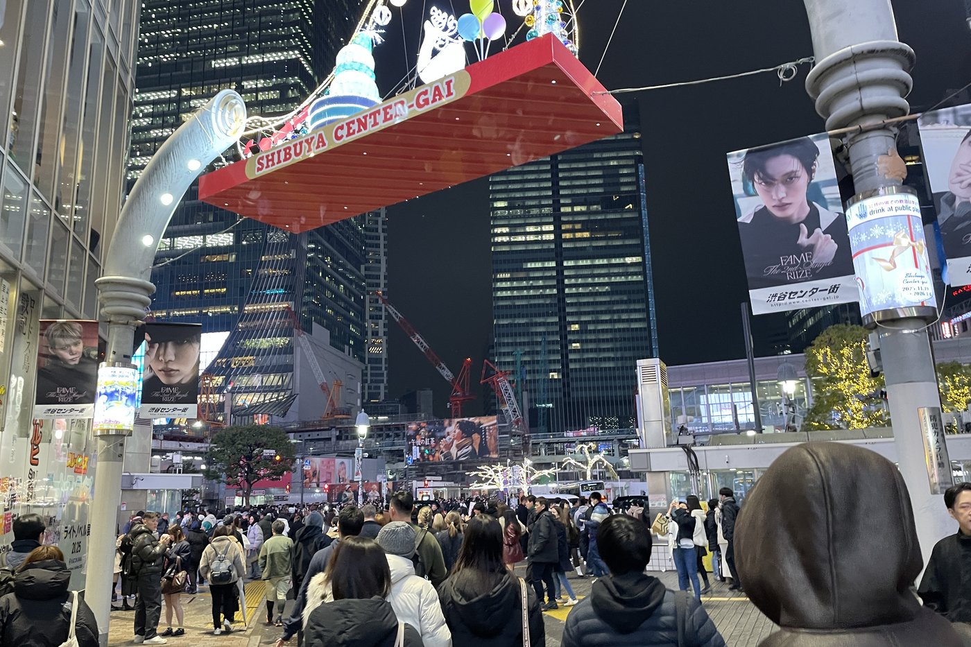 Foule sous l'arche lumineuse de Shibuya Center-Gai le soir de Noël, gratte-ciel illuminés en arrière-plan.