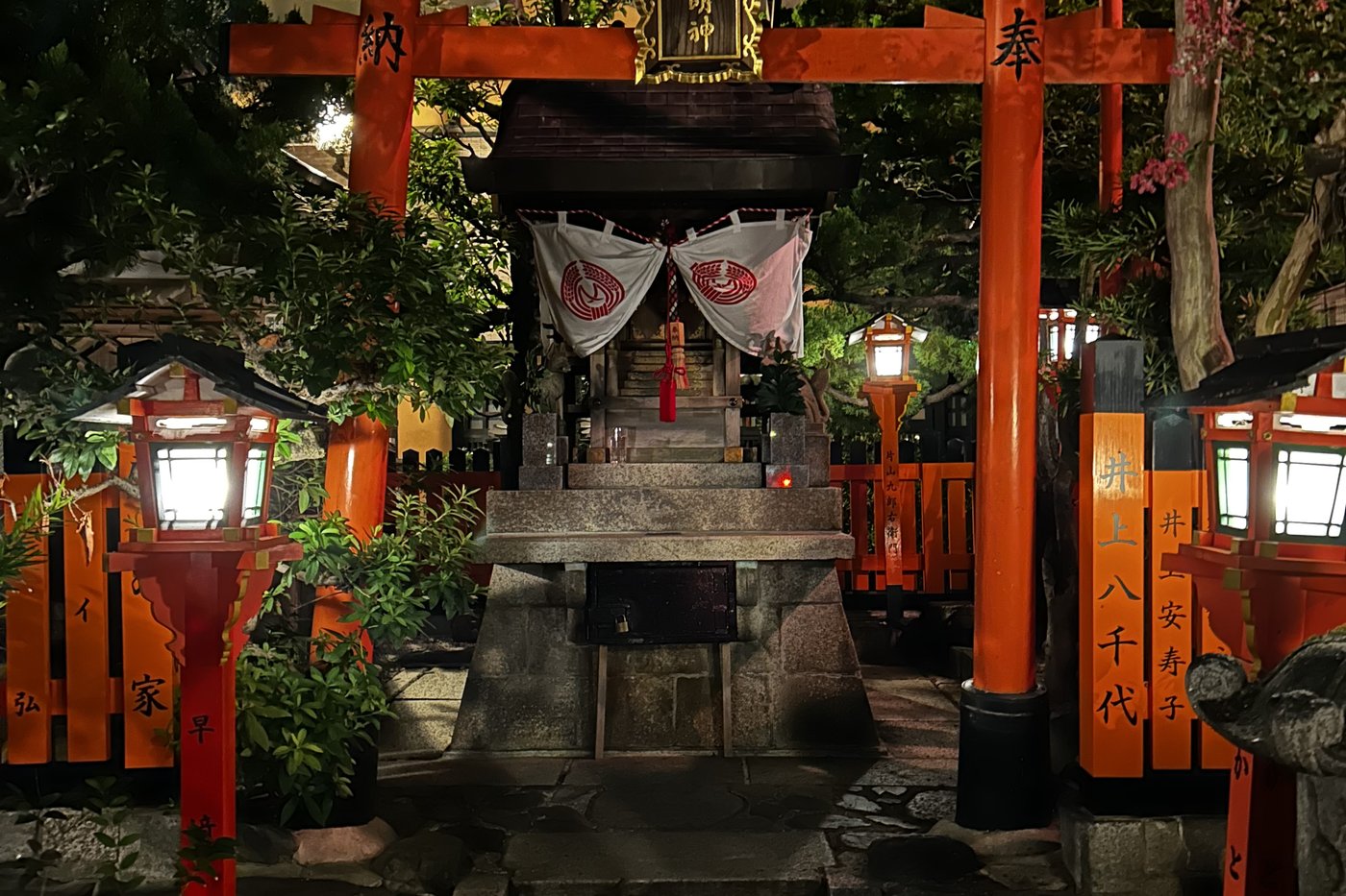 Petit sanctuaire Tatsumi Daimyōjin éclairé la nuit sous un torii rouge, dans le quartier de Gion à Kyoto.
