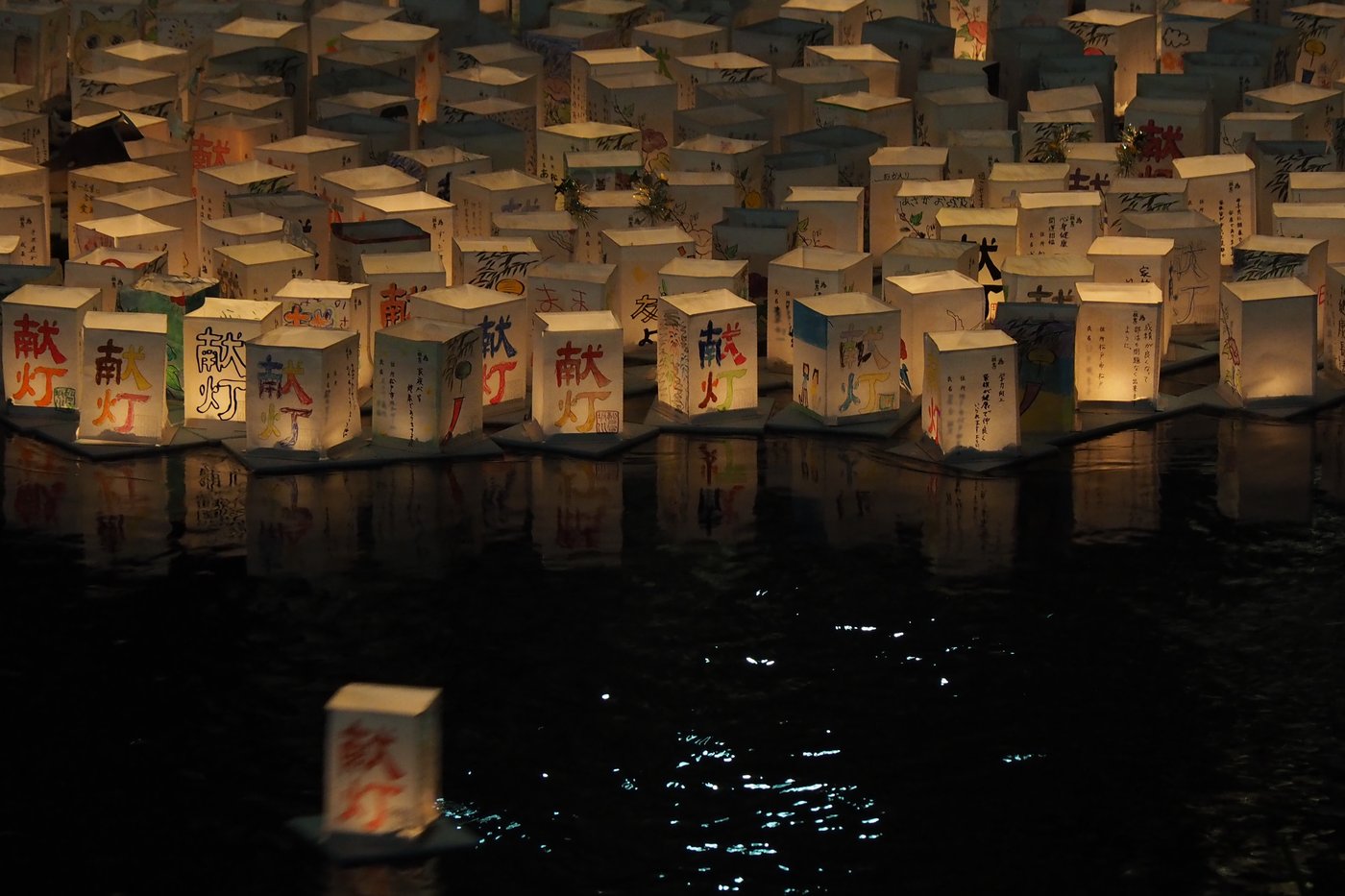 Lanternes de papier flottant sur une rivière la nuit, cérémonie de tōrō nagashi pour Obon, à Matsudo (Chiba).