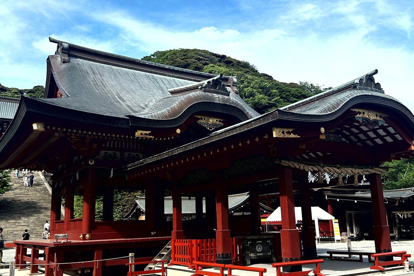 Bâtiments laqués rouge du sanctuaire Tsurugaoka Hachimangū à Kamakura, sous un ciel bleu.