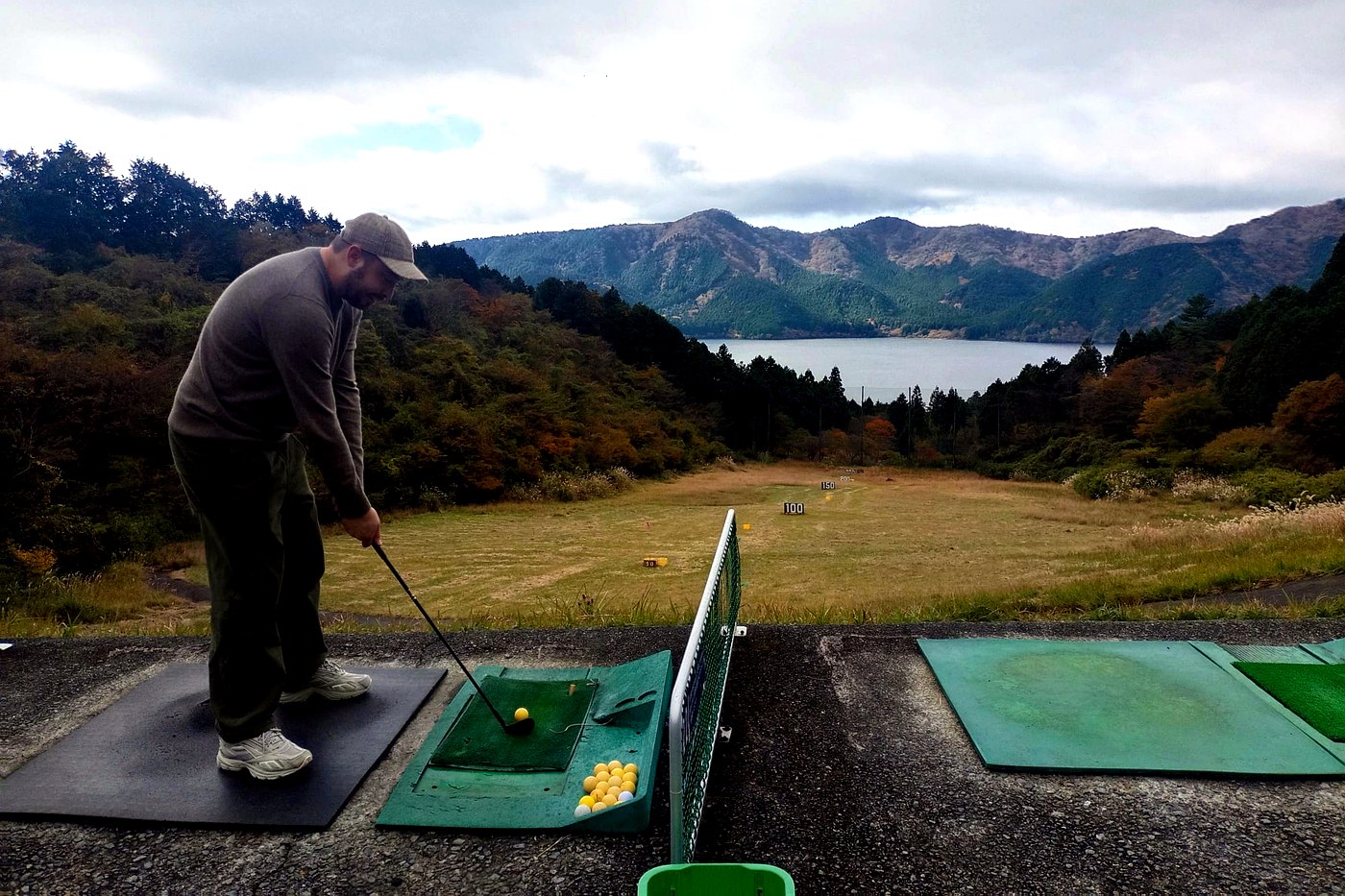 An open-air driving range above Lake Ashi and the Hakone mountains.