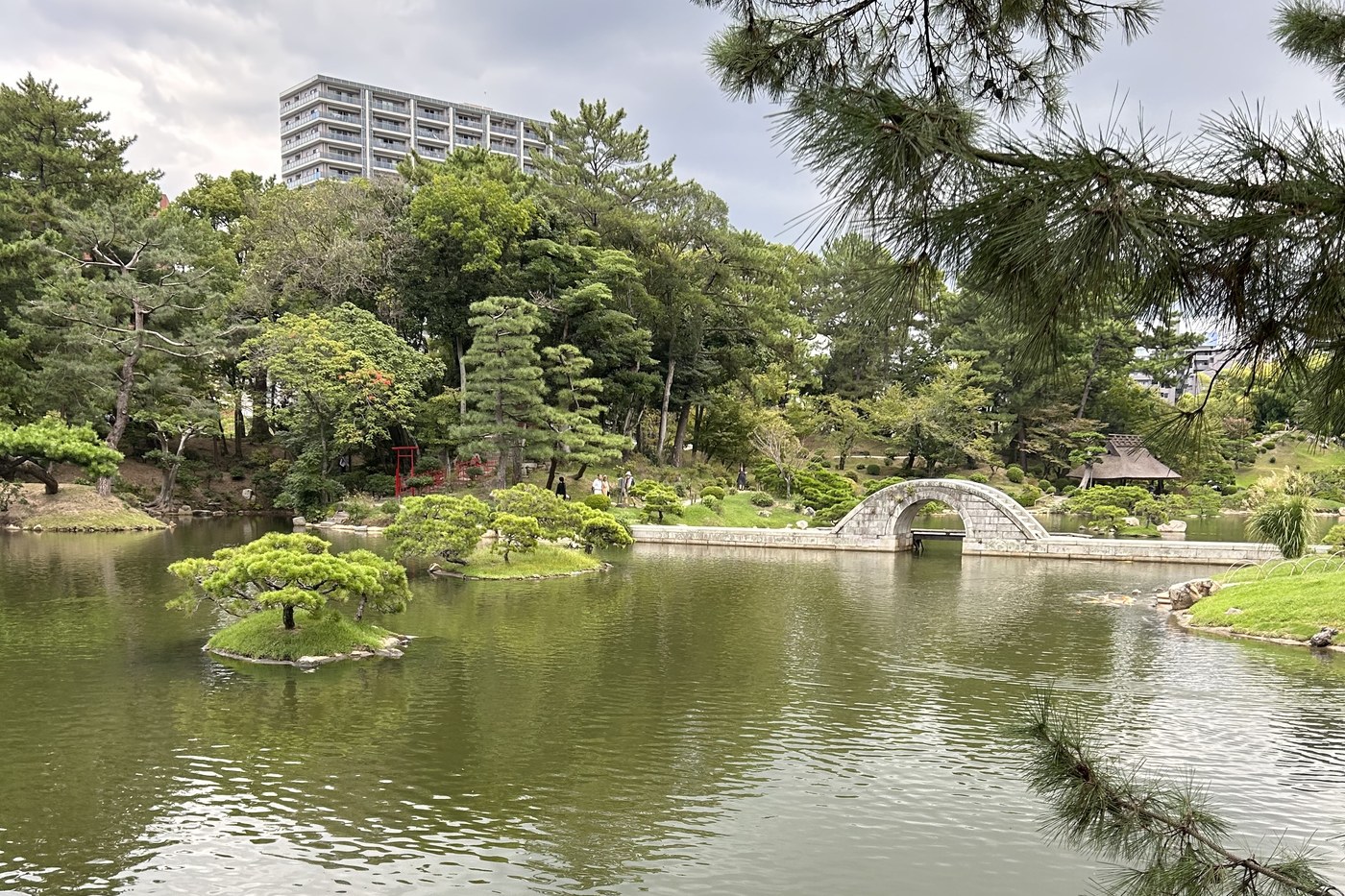 The arched stone bridge of Shukkei-en garden in Hiroshima, islets and pines in the foreground.