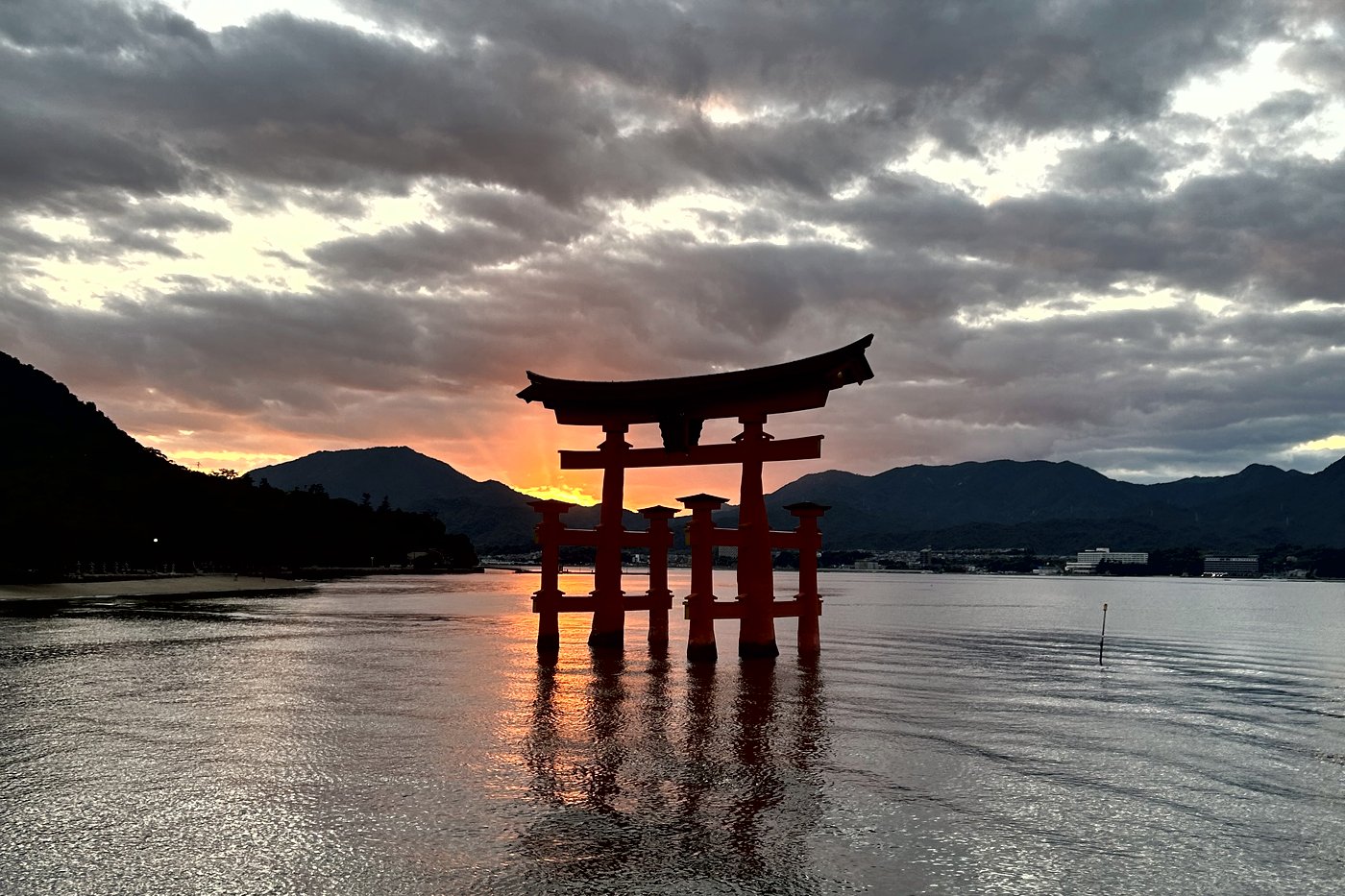 The floating torii of Itsukushima shrine at high tide, a red outline at sunset on the Seto Inland Sea.