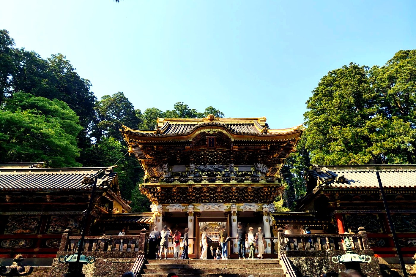 The richly gilded and carved Yomeimon gate of Toshogu shrine in Nikko, under a blue sky.
