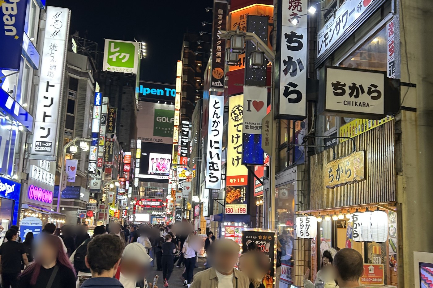 A busy Kabukicho lane in Tokyo at night, neon signs and crowds.